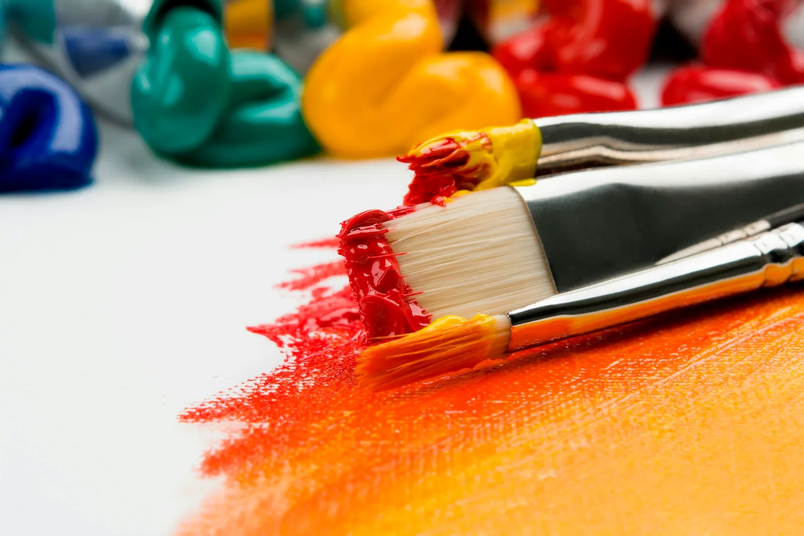 Three paint brushes with fresh acrylic paint on the bristles